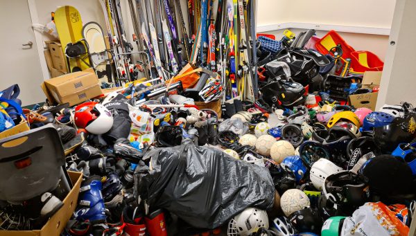 Ett rum full med olika utrustning. Hockeyhjälmar, klubbor, skidor med mera.